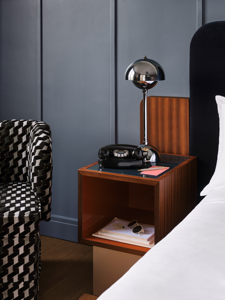 Bedside table with lamp phone and cosy chair beside