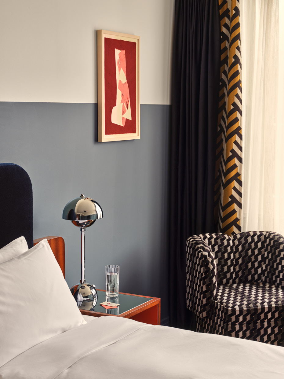 Close up of armchair and bedside table and wall art next to bed