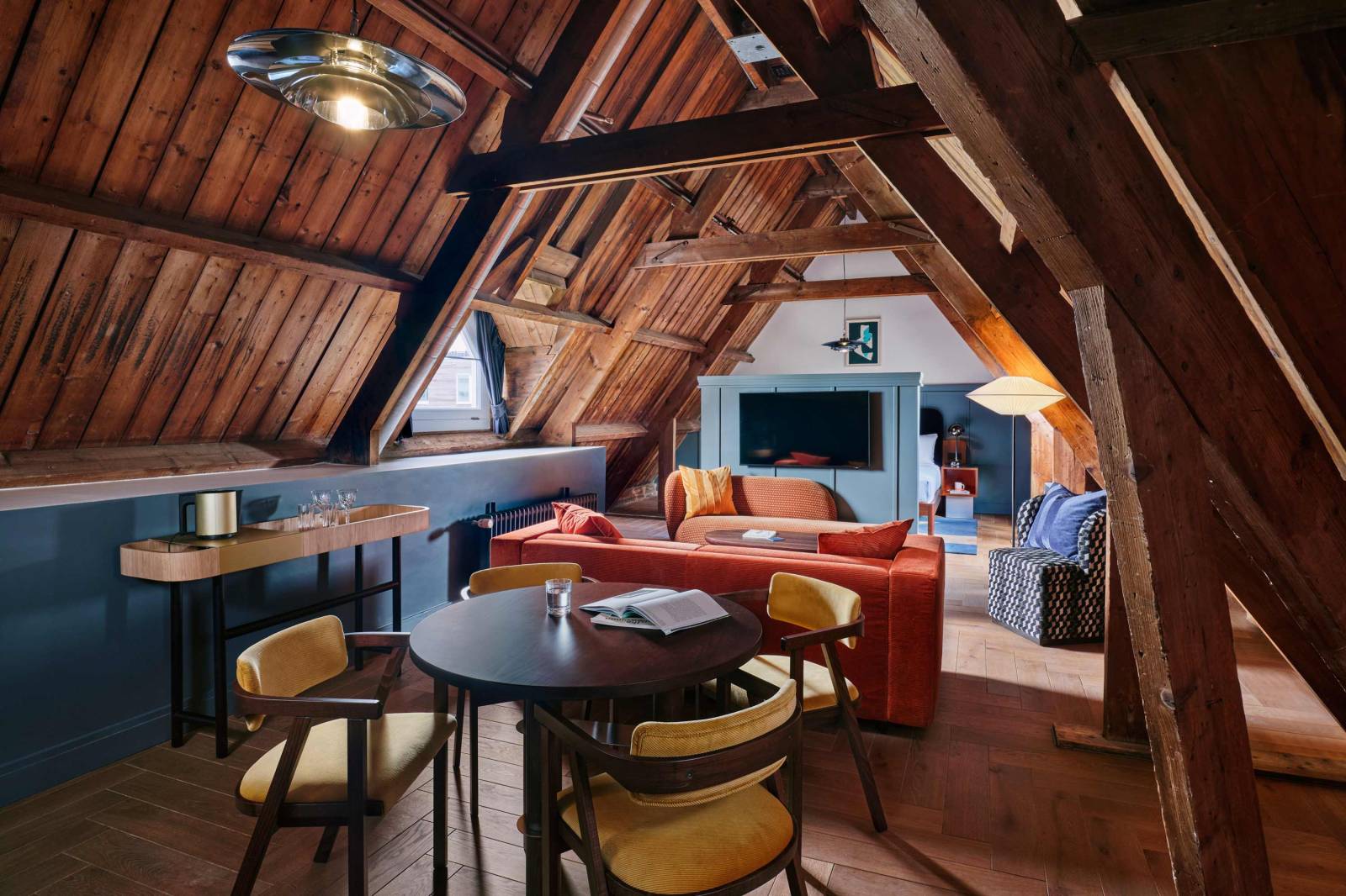 Wide view o the Studio room with TV, sofa, table and chairs, window and kitchenette