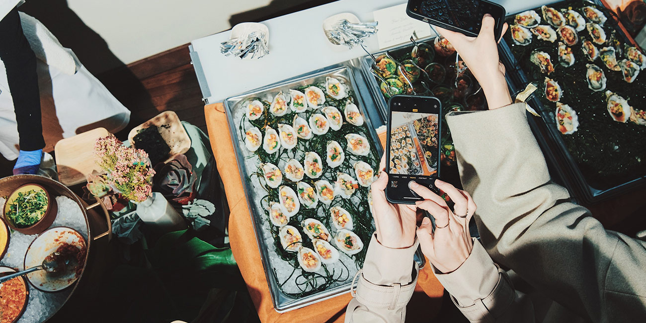 A group of people take snaps of a plate of oysters at an LA party at the Hoxton.