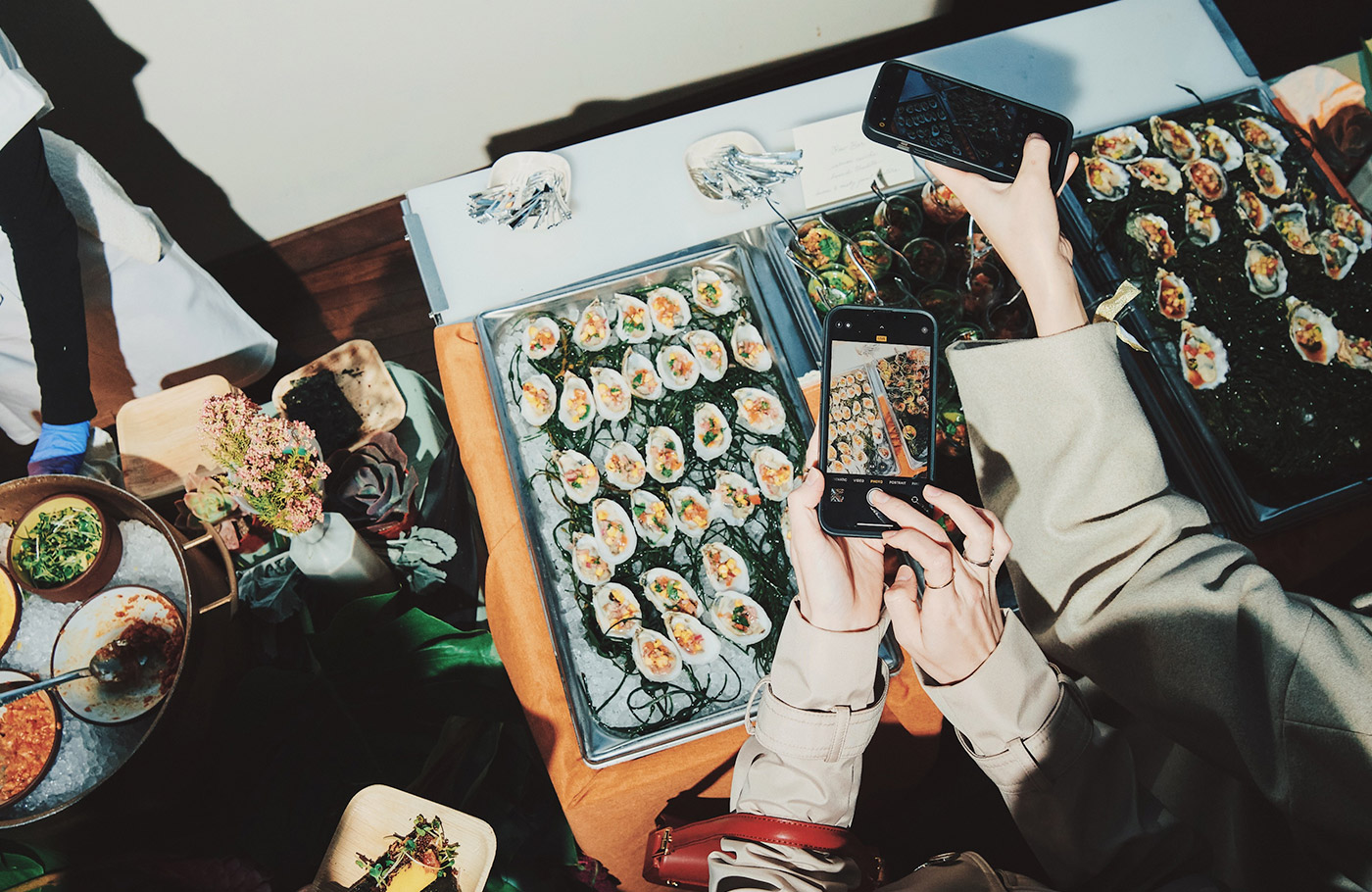 A group of LA party-goers take photos of a tray of dressed oysters.