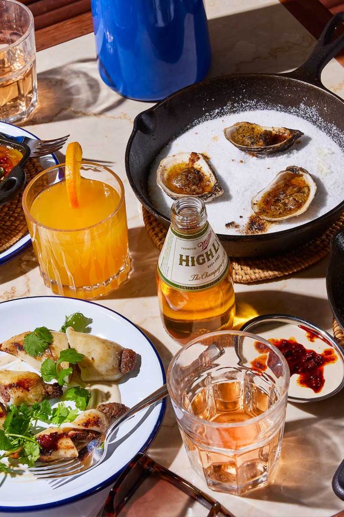 Close up of scallops and oysters served alongside cocktails and beer.