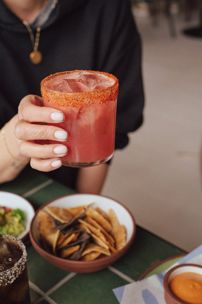 A woman holds a cocktail with an orange dusting around the rim.