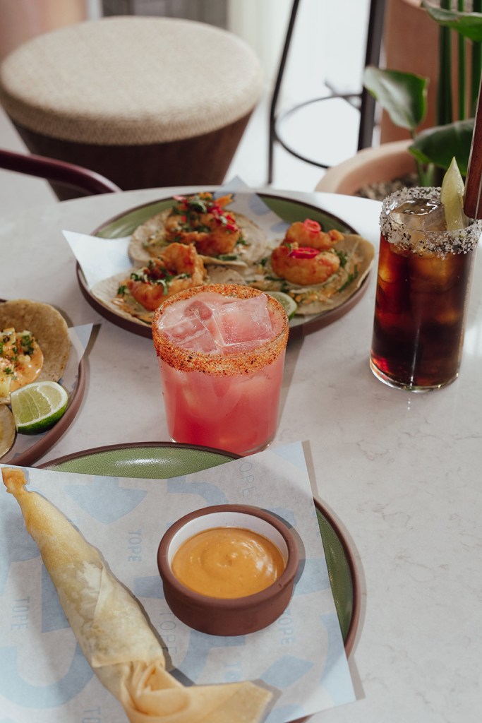 Tacos and a cocktail served on a marble tabletop.