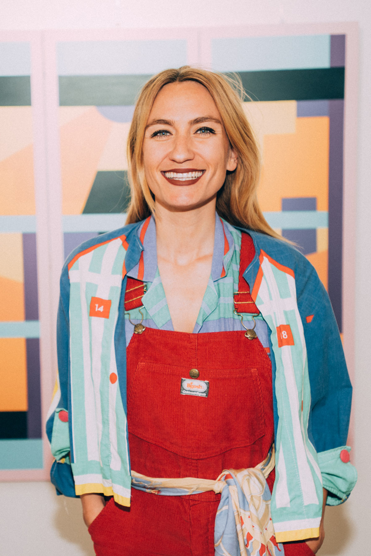 Parisian artist Caroline Derveaux smiles in front of her artwork