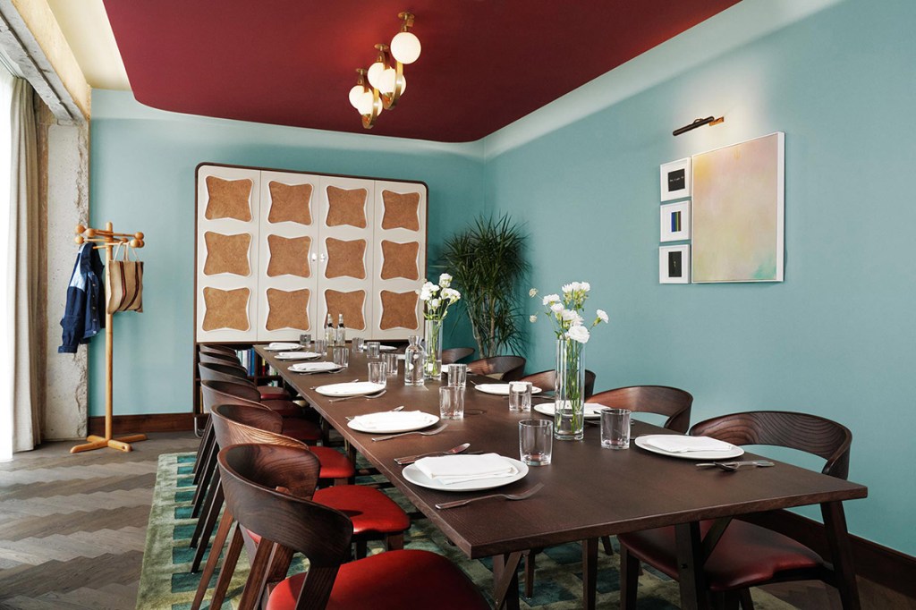 Interior of the dining room, laid out for lunch with table flowers, chandelier and wall art.