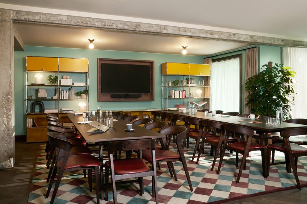 Living Room laid out for a meeting with a wall-mounted monitor on the paster green wall.