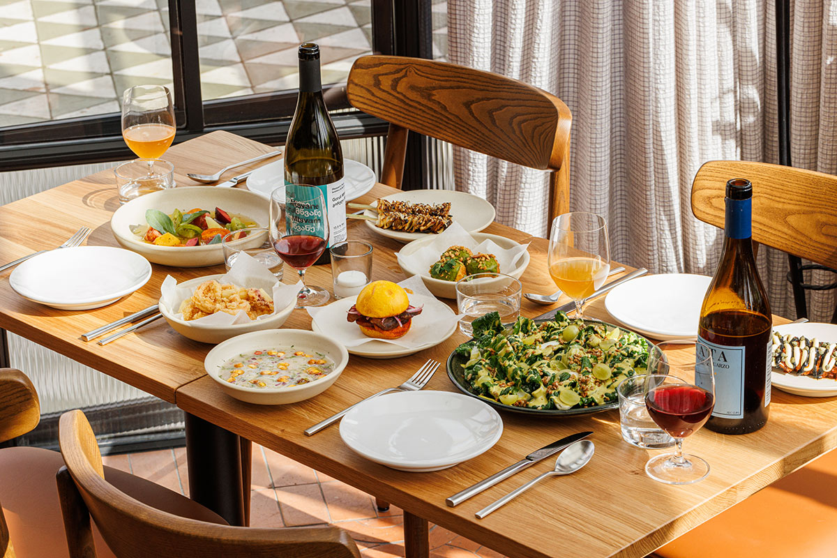 Wooden table laid for four diners with bottles of wine, cerviches and other delicious and healthy Peruvian dishes.