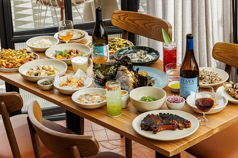 A table filled with dishes on offer at Llama Inn including wine, cocktails, fish, rice, chips, steaks and much more.