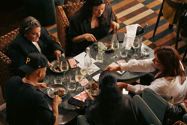 four people sitting in comfortable chairs eating around a table.