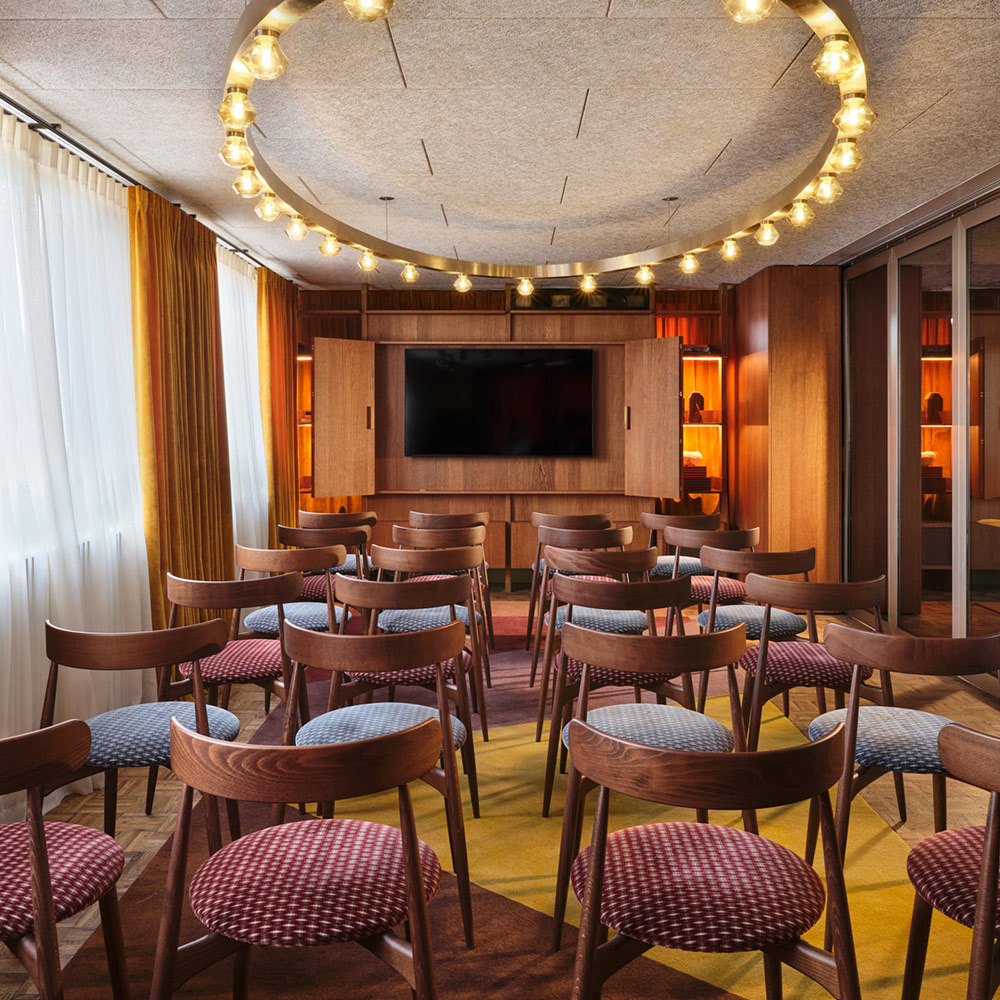 Rows of seats face a screen in a meeting room with lots of natural light