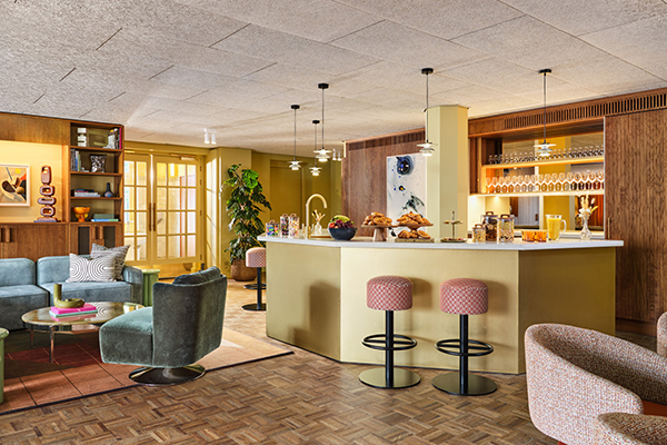 Pantry interior with wooden floors, stools and arm chairs, counter for food, fridge and lots of floor space.