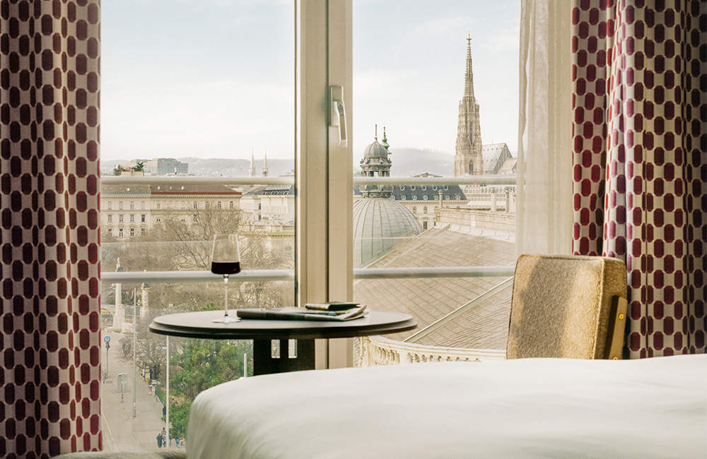 Table and chair next to a large window with a stunning view of Vienna.