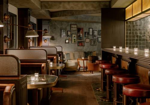 view of a long aisle with private booths on the left and a bar with barstools on the right