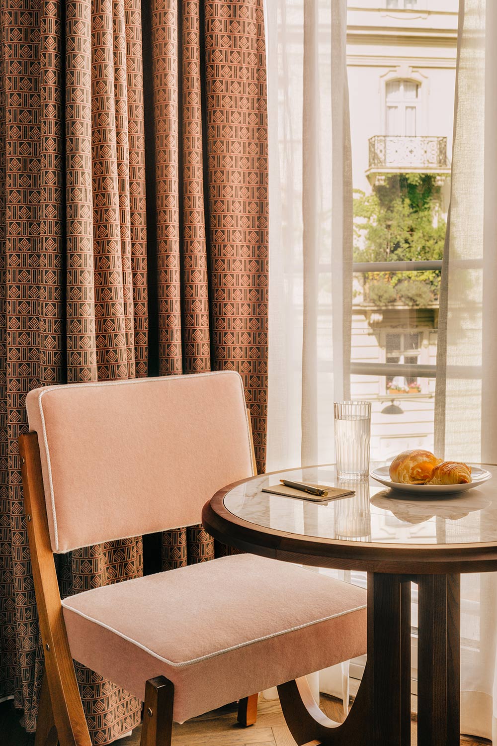 Chair by a coffee table next to a window and a fresh pastry ready to eat
