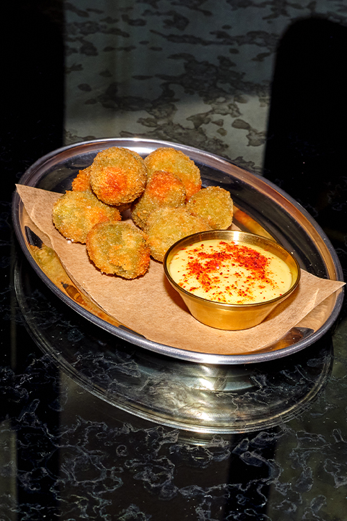 Tray of fried olives with aioli served on a silver tray.