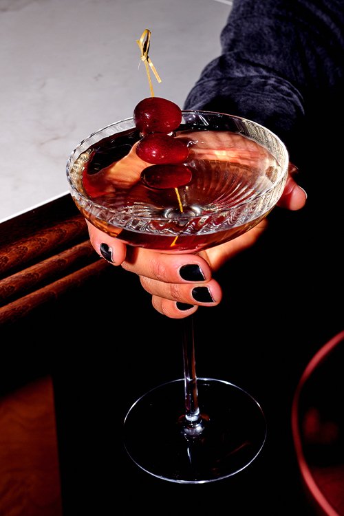 Cocktail in martini glass with red grape.