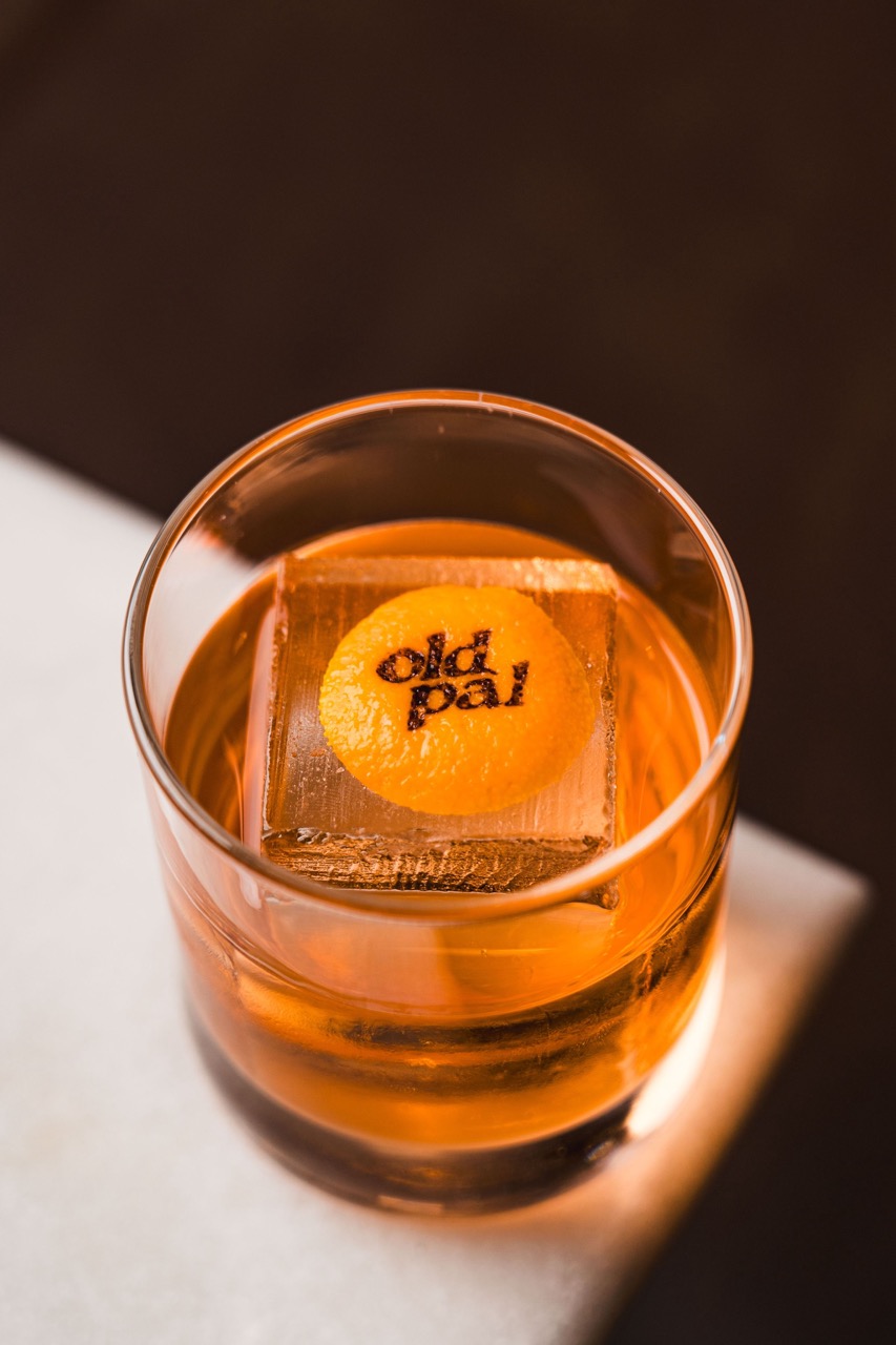 A low cocktail with a round ice cube with the old pal logo burnt into it.