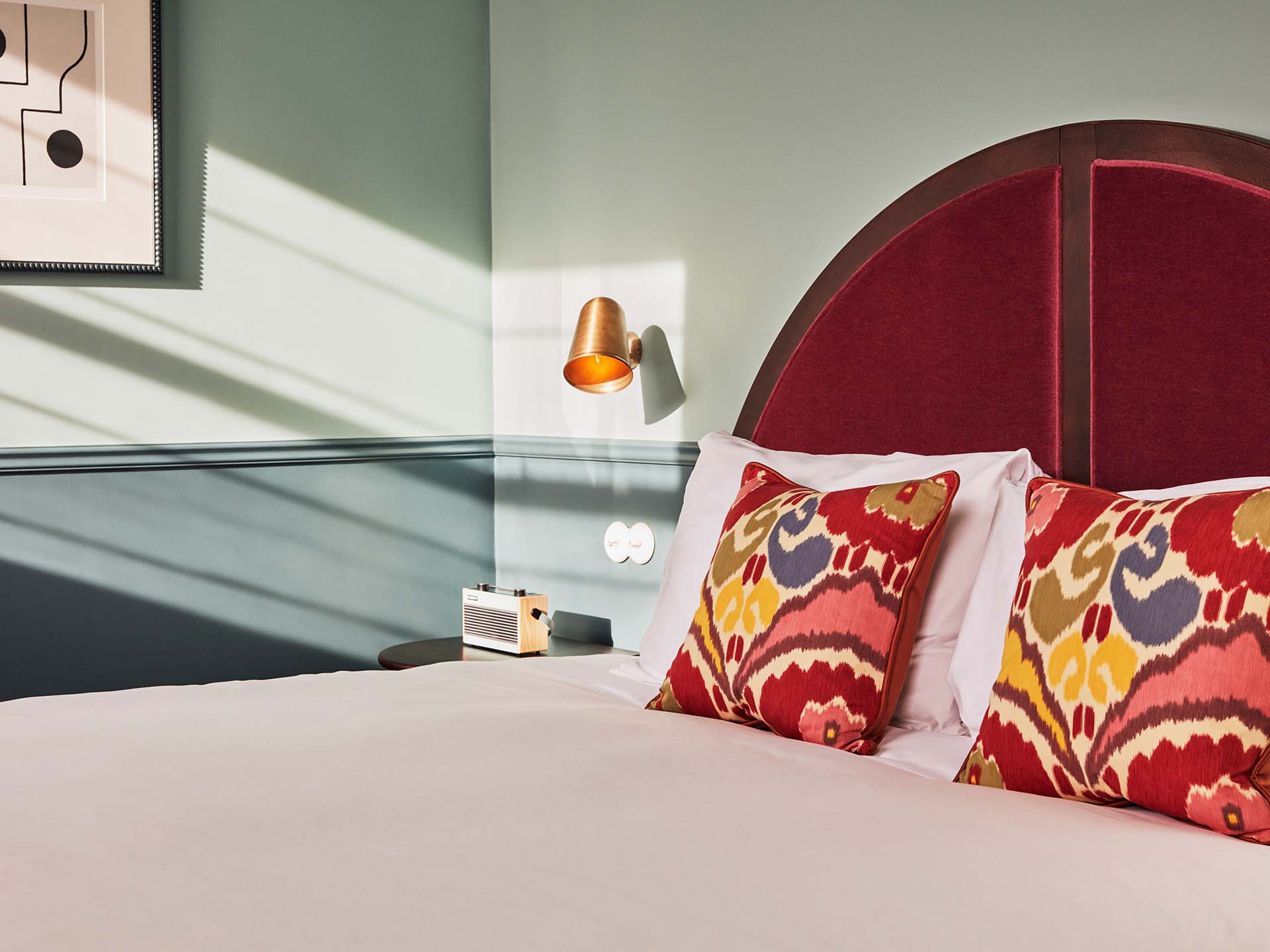 Hotel room decor showcasing, red velvet bedboard with decorative cushion on the bed.