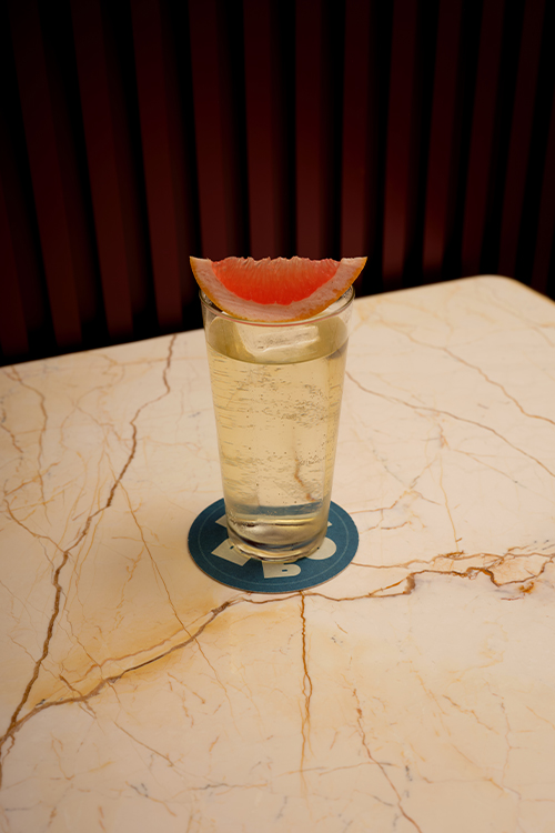 Tall aperitif drink served with a wedged of pink grapefruit.