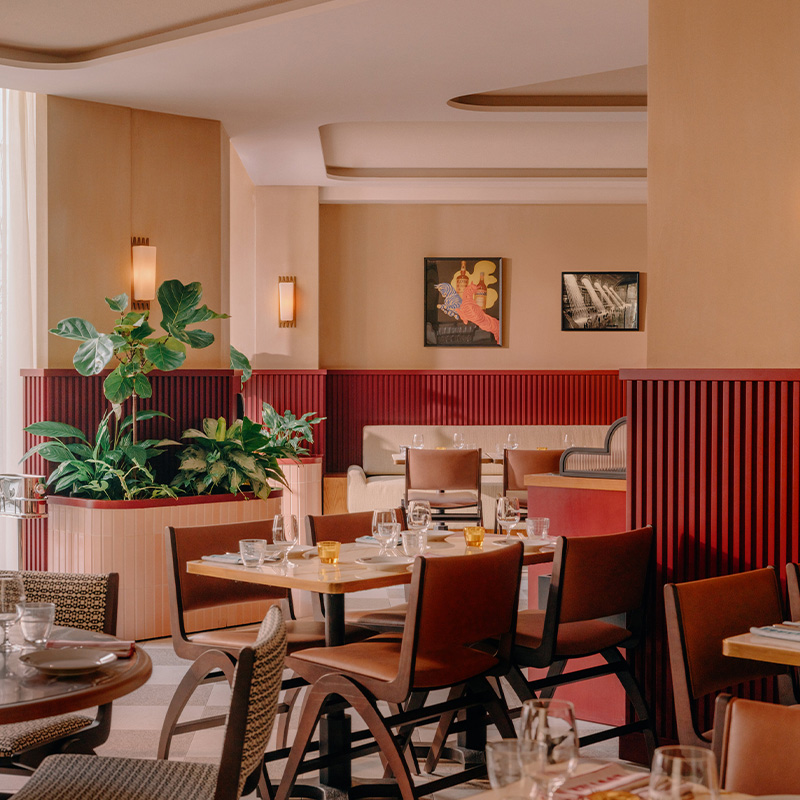 The interior of the bouvier, with tables and chairs and a large window, gives natural light.