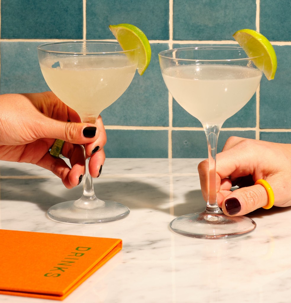 Due mani che reggono ciascuna un Daiquiri Classico, con un menu accanto.
