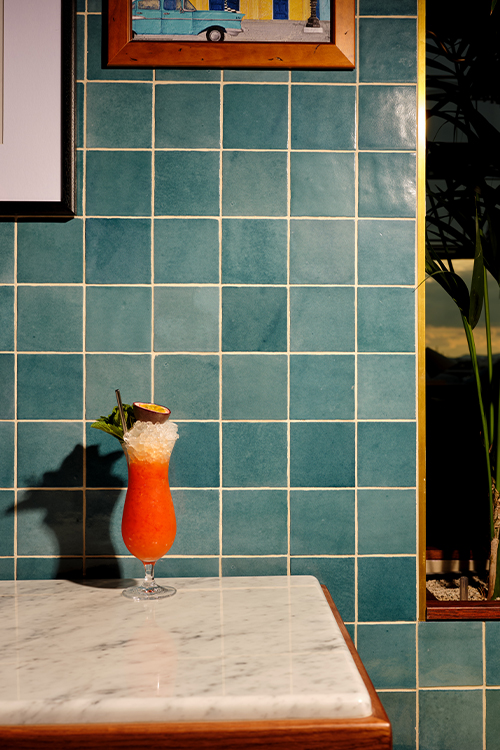 Tall bright cocktail on marble table and pictures hanging above.