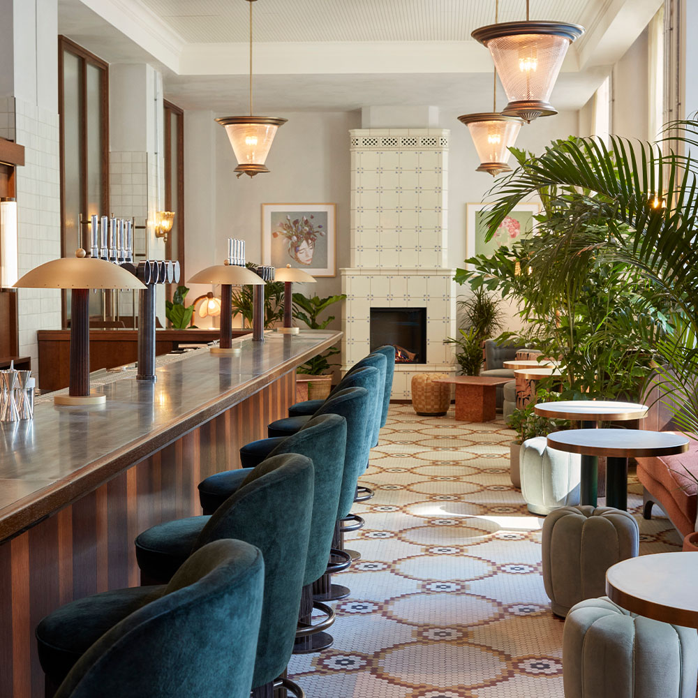long bar counter top with blue velvet chair and nooks with intimate seating areas.