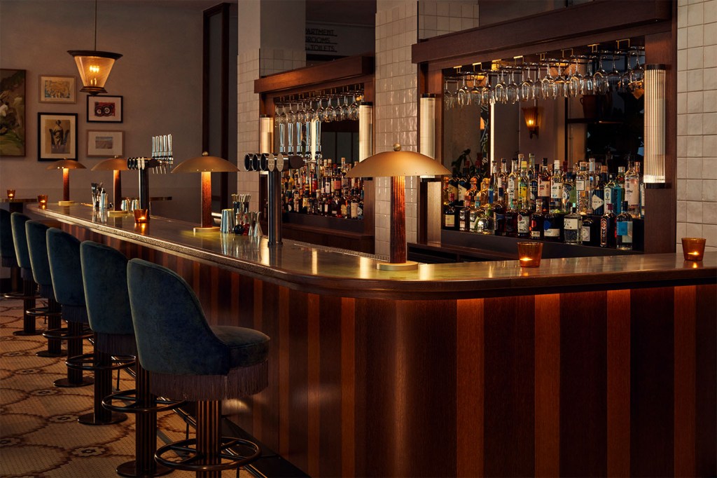 Fully stocked bar with large L-shape bar counter with bar stools along it.