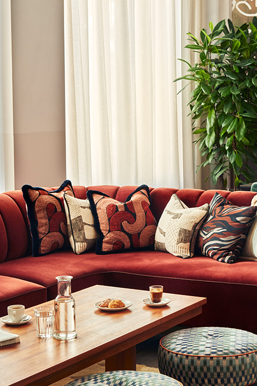 lush red velvet sofa with coffee table and pouffe seating.