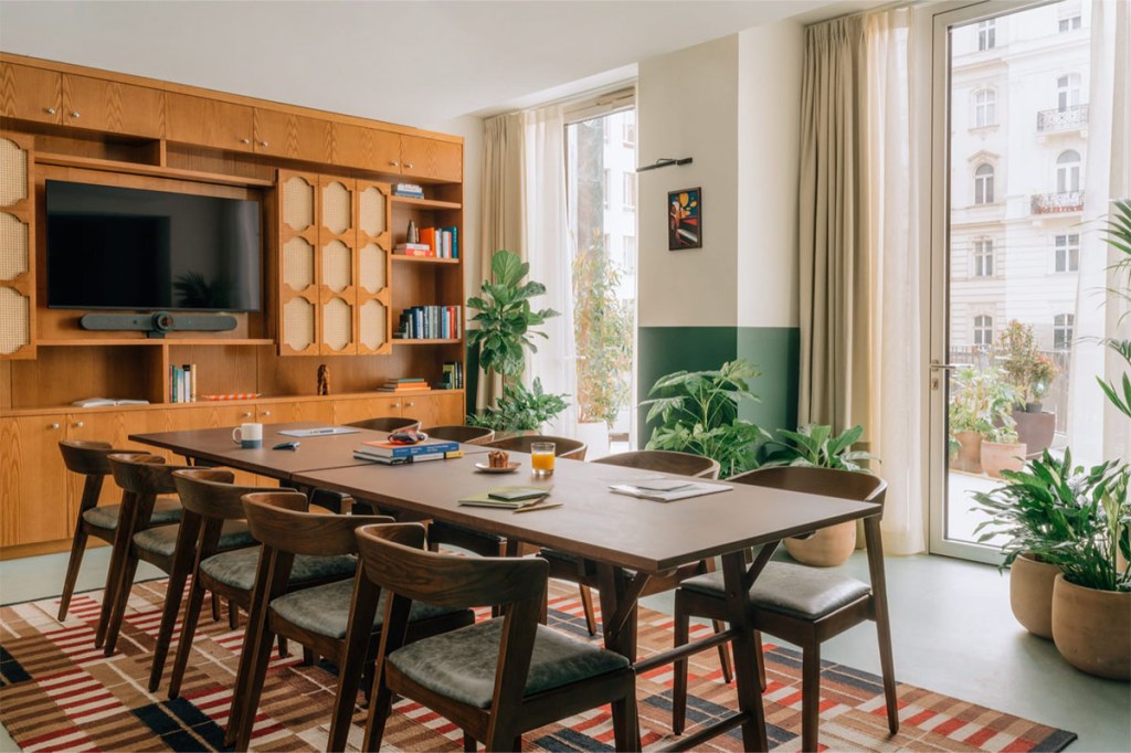 Large windowing giving natural light into the room and on the long table and chairs.