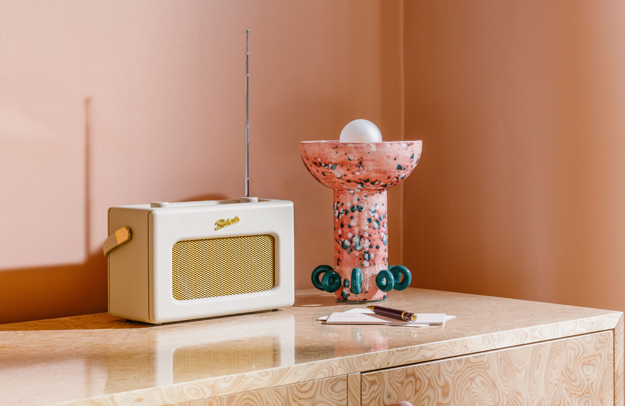 Radio and a coral and pink glass lamp resting on a table.