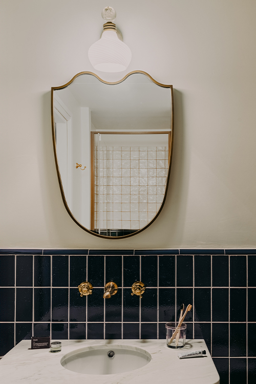 Gold-framed bathroom mirror above a marble basin.