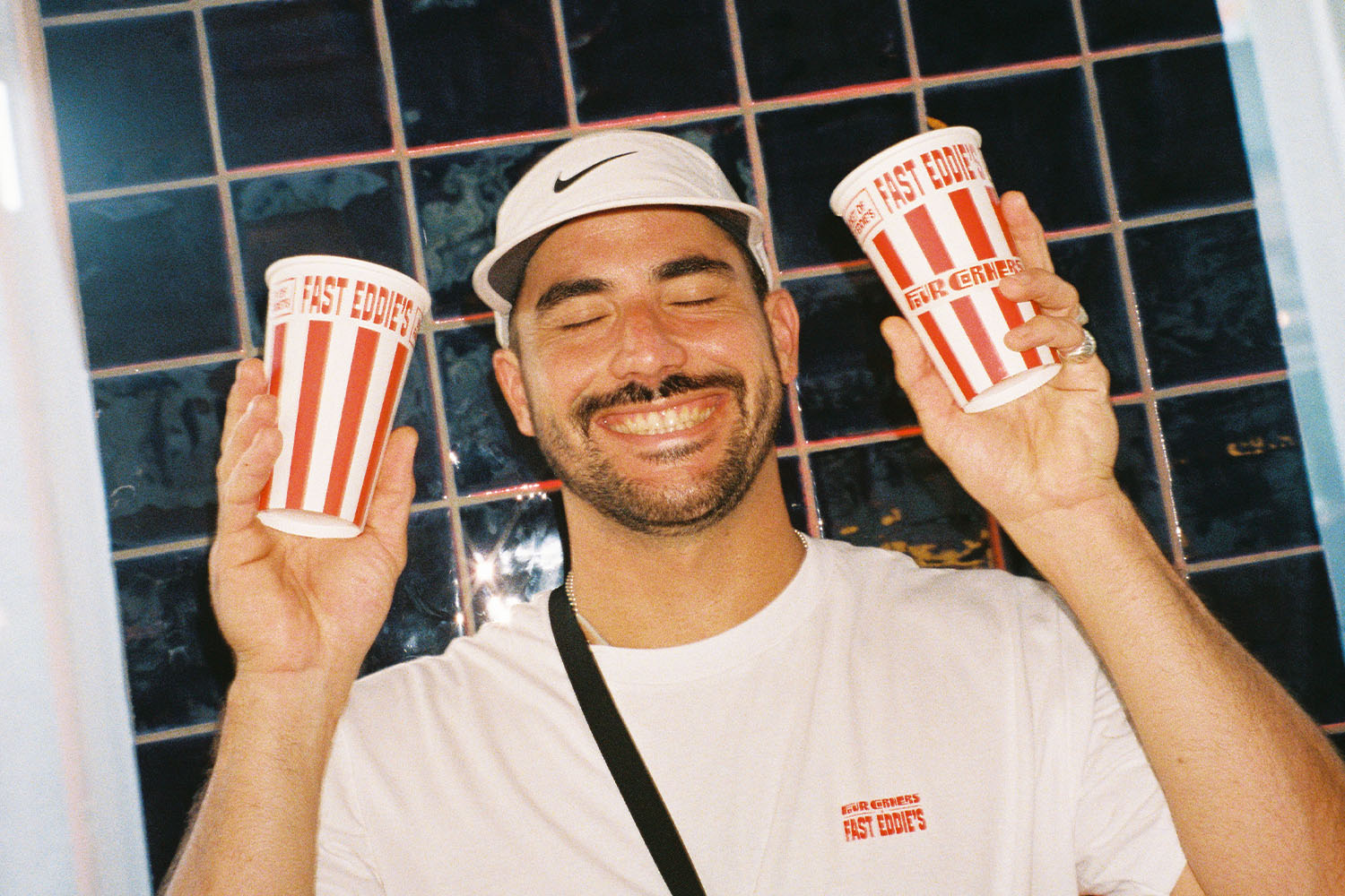 Eddie holding two soft drinks containers with his burger branding.
