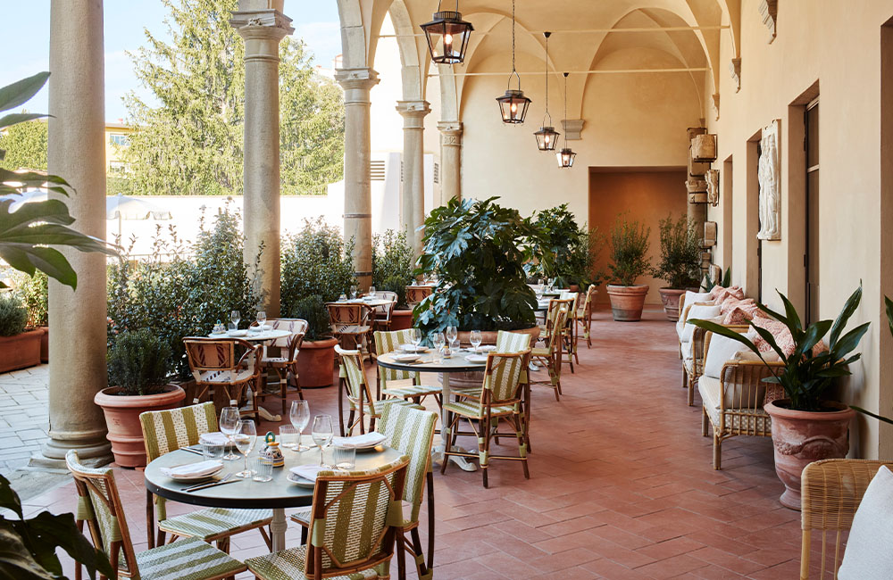 Alassio open terrace with a courtyard view, abundant natural light, shaded areas, and lush greenery.