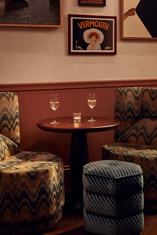 Set of soft, symmetrical-patterned chairs around a table, with two glasses of white wine.