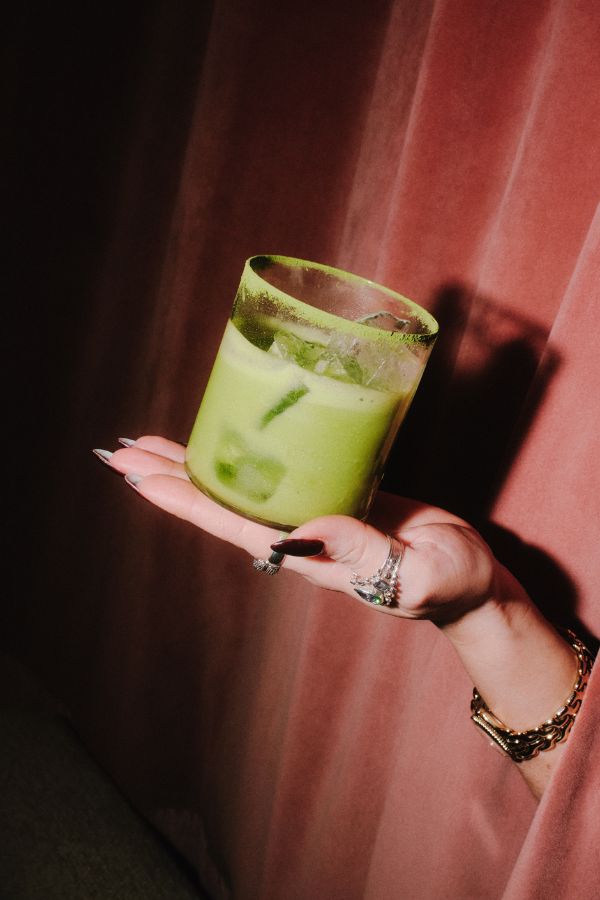 A hand holding a refreshing milk green ice beverage.